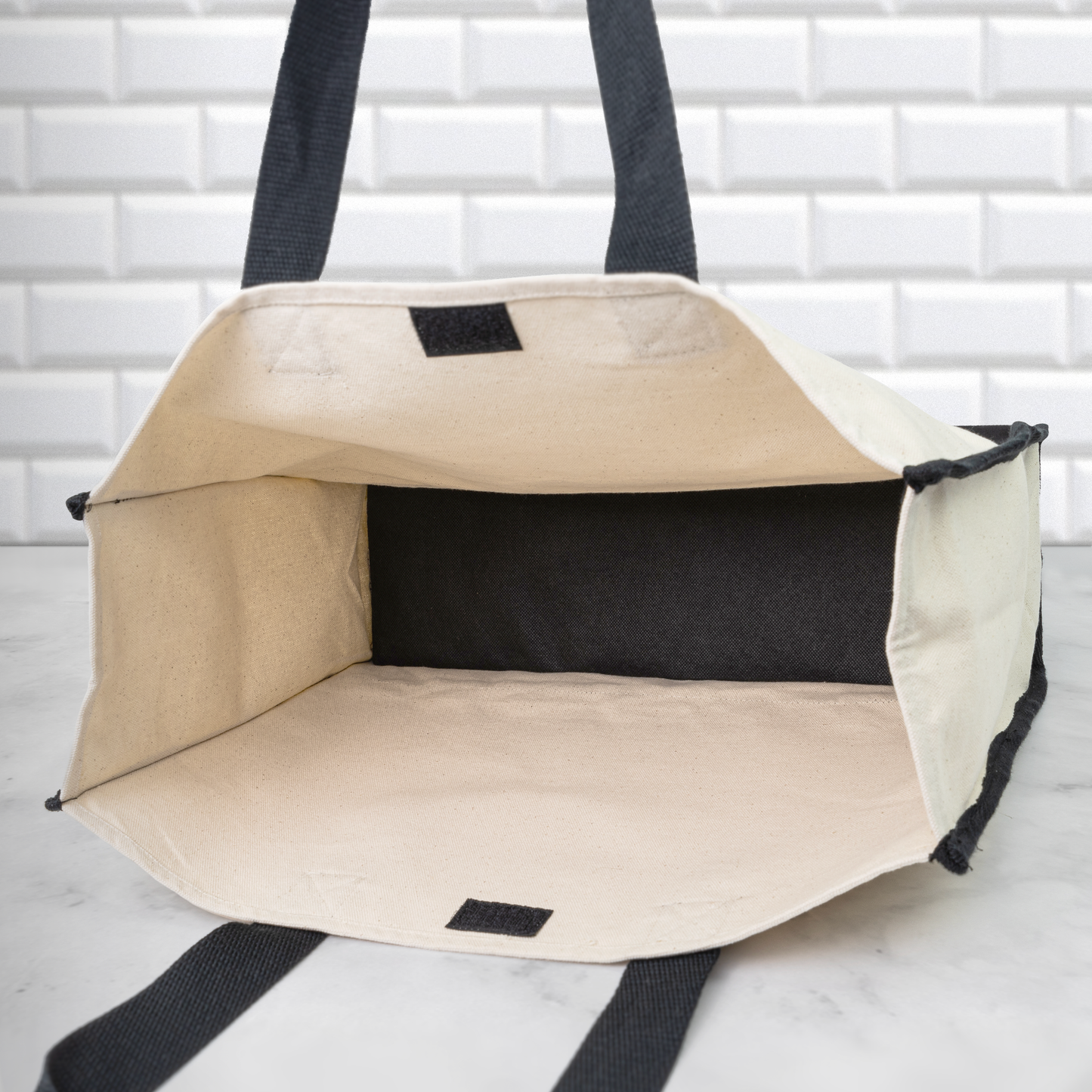 Beige pet carrier with black interior and straps on a white background