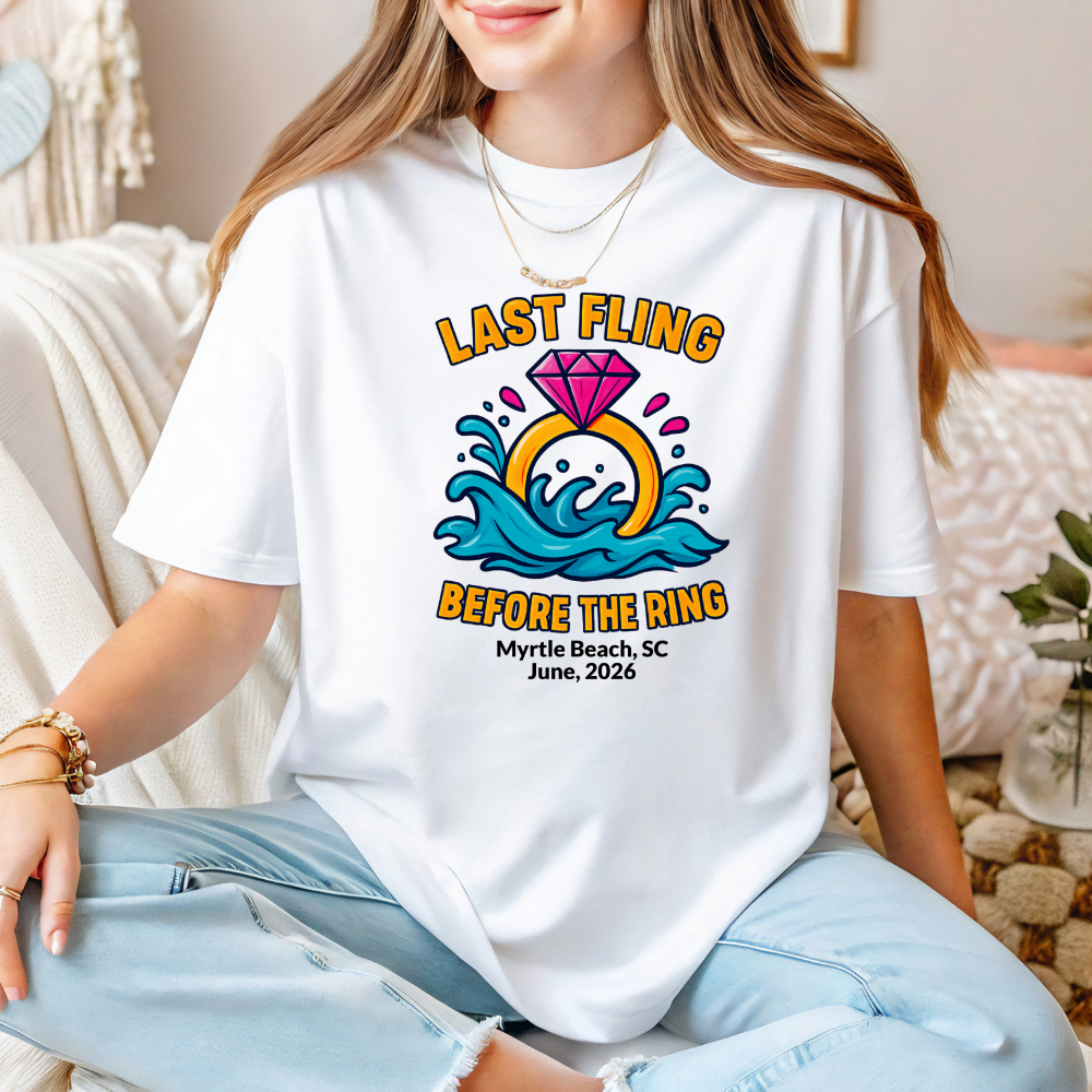 Person wearing a white t-shirt with a colorful graphic and text, sitting on a couch.