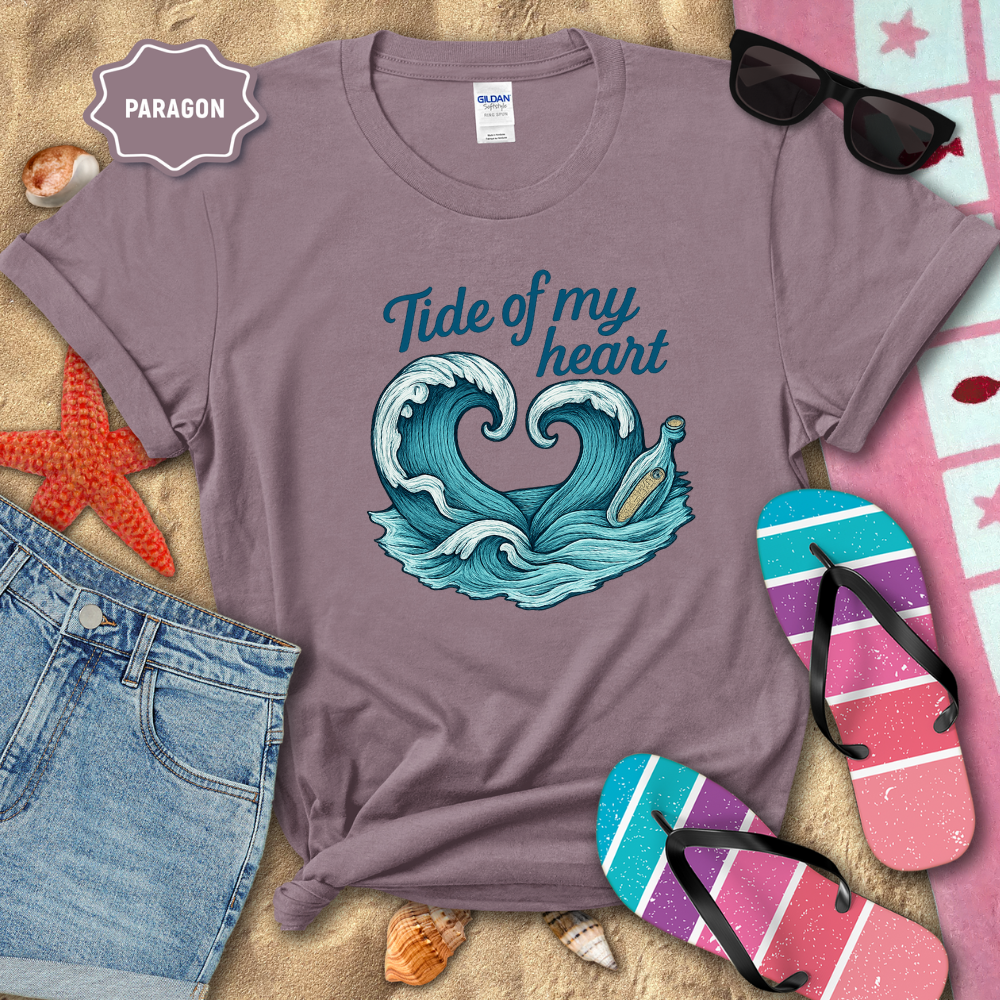 Purple t-shirt with 'Tide of my heart' design on a sandy background with beach accessories.