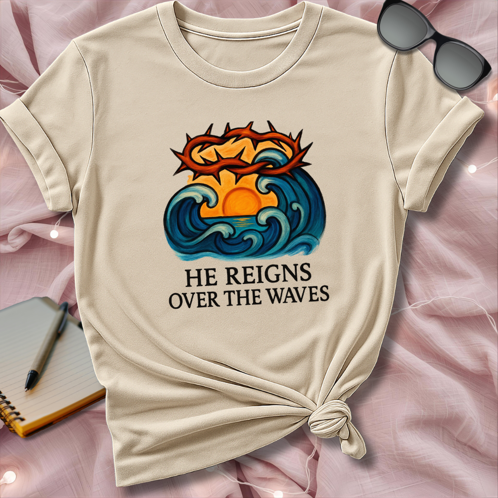 Beige t-shirt with a graphic design and text on a pink surface with sunglasses and notebook.