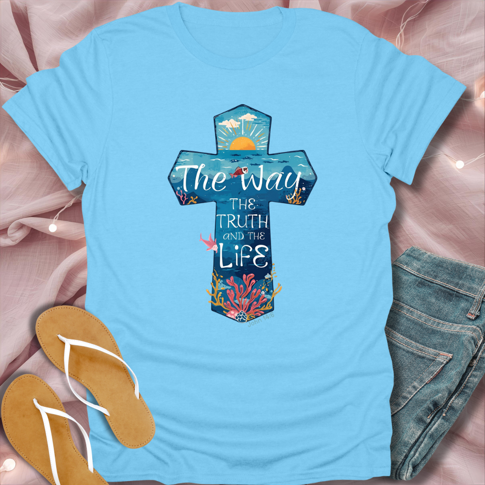 Light blue t-shirt with a cross design and text on a pink fabric background