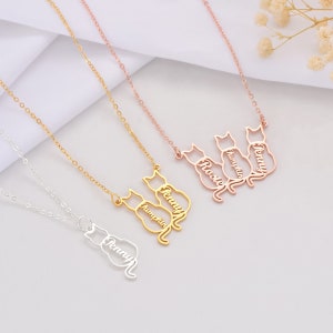 Gold necklaces with cat designs on a light gray background