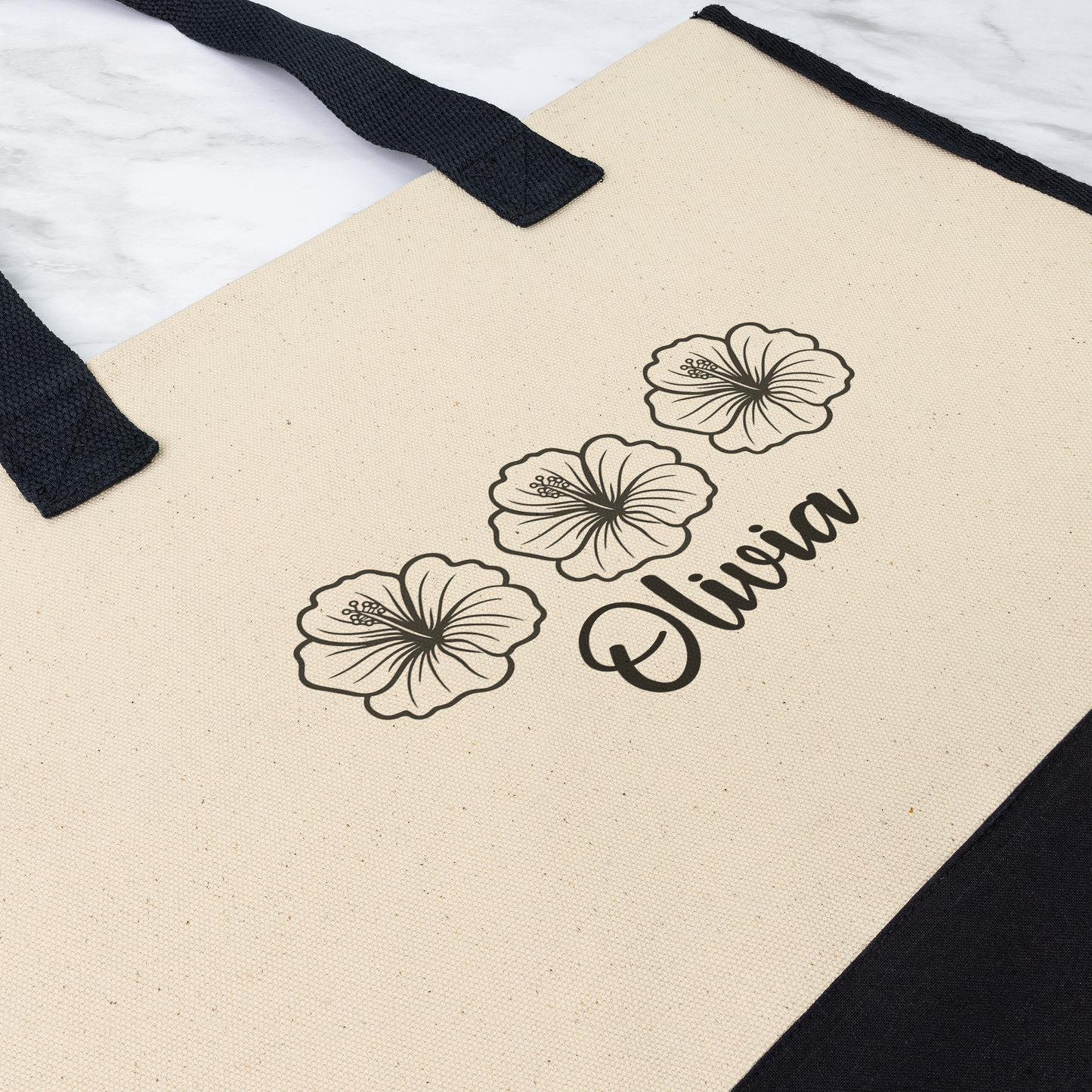 Beige tote bag with black floral designs and the name 'Olivia' on a white background