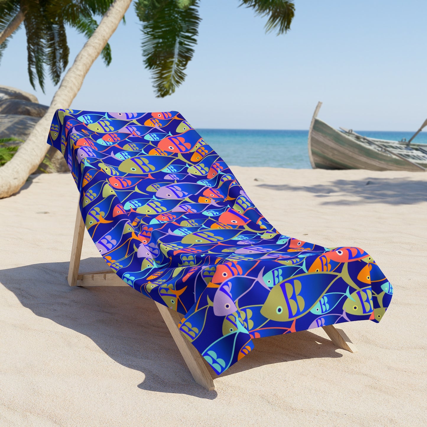 Colorful fish-patterned towel draped over a beach chair on a sandy beach with palm trees and ocean in the background.