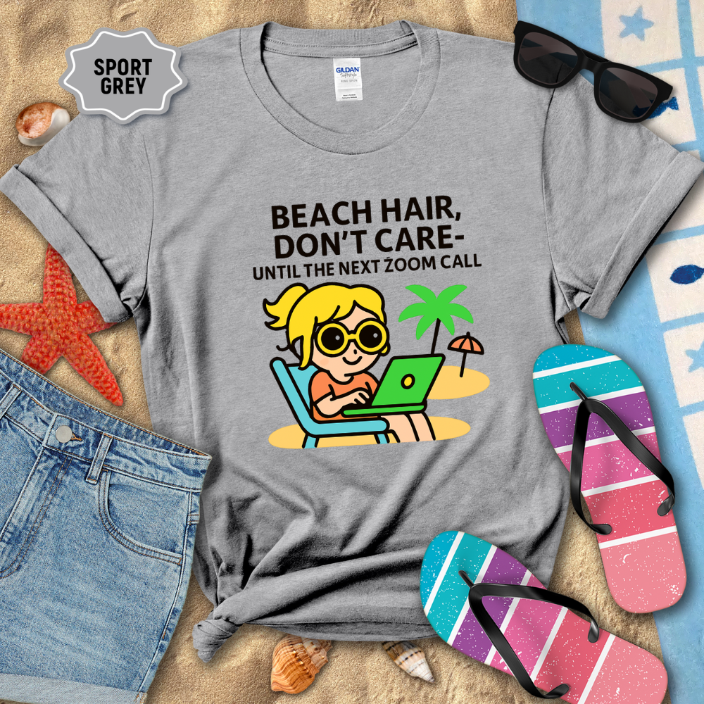 Gray t-shirt with beach-themed design and text, surrounded by beach accessories on a sandy background.