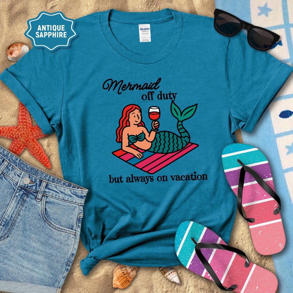 Blue t-shirt with mermaid graphic and text on a beach-themed background