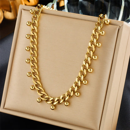 Close-up of nature-inspired 18K gold necklaces with thick chain and delicate round balls