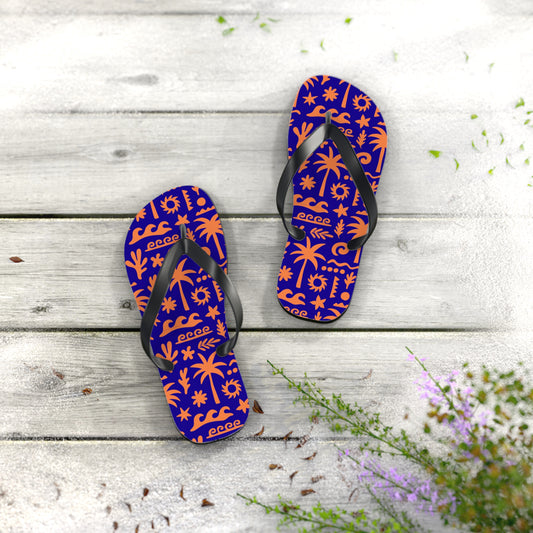 Pair of purple flip-flops with orange patterns on a wooden surface with flowers.