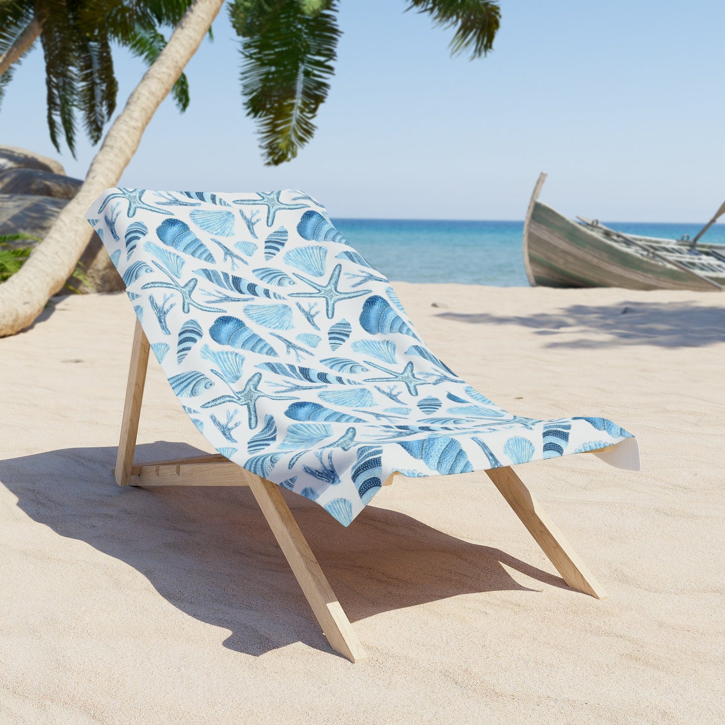 Beach chair with a blue and white patterned towel on a sandy beach with palm trees and ocean in the background.