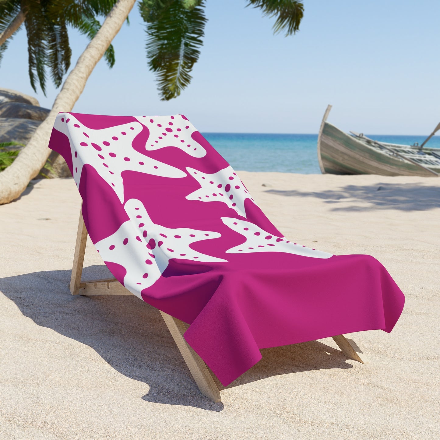 Beach chair with a pink and white patterned towel on a sandy beach with palm trees and a boat in the background.