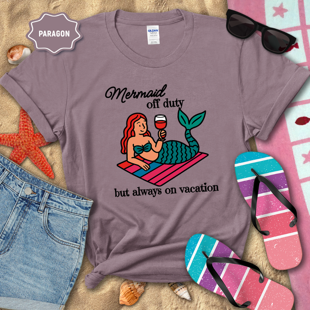 Purple t-shirt with mermaid graphic and text on a beach-themed background
