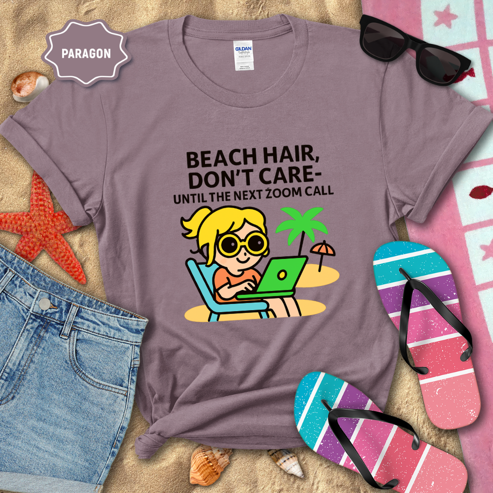 Purple t-shirt with beach-themed graphic and text, surrounded by beach accessories on sand.