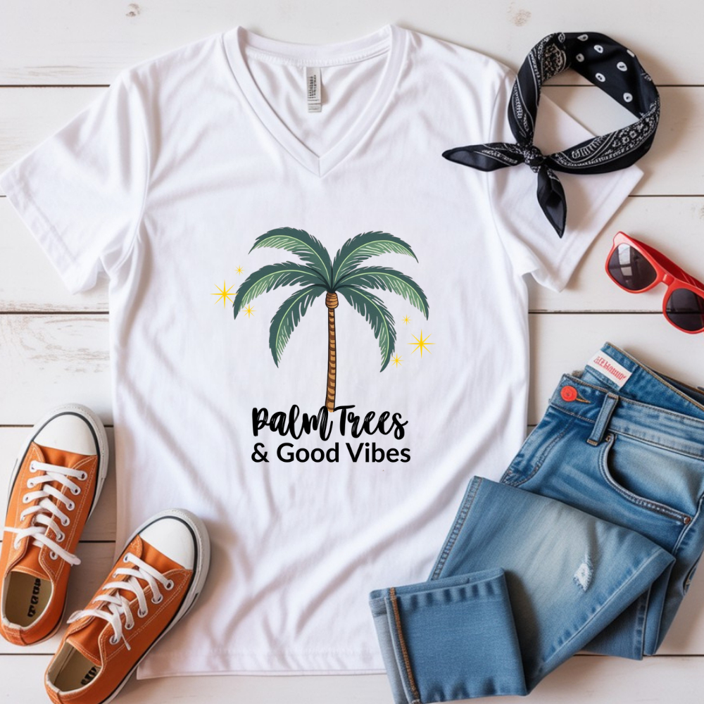 White t-shirt with palm tree design and text, paired with orange sneakers, blue jeans, and a black bandana on a wooden surface.