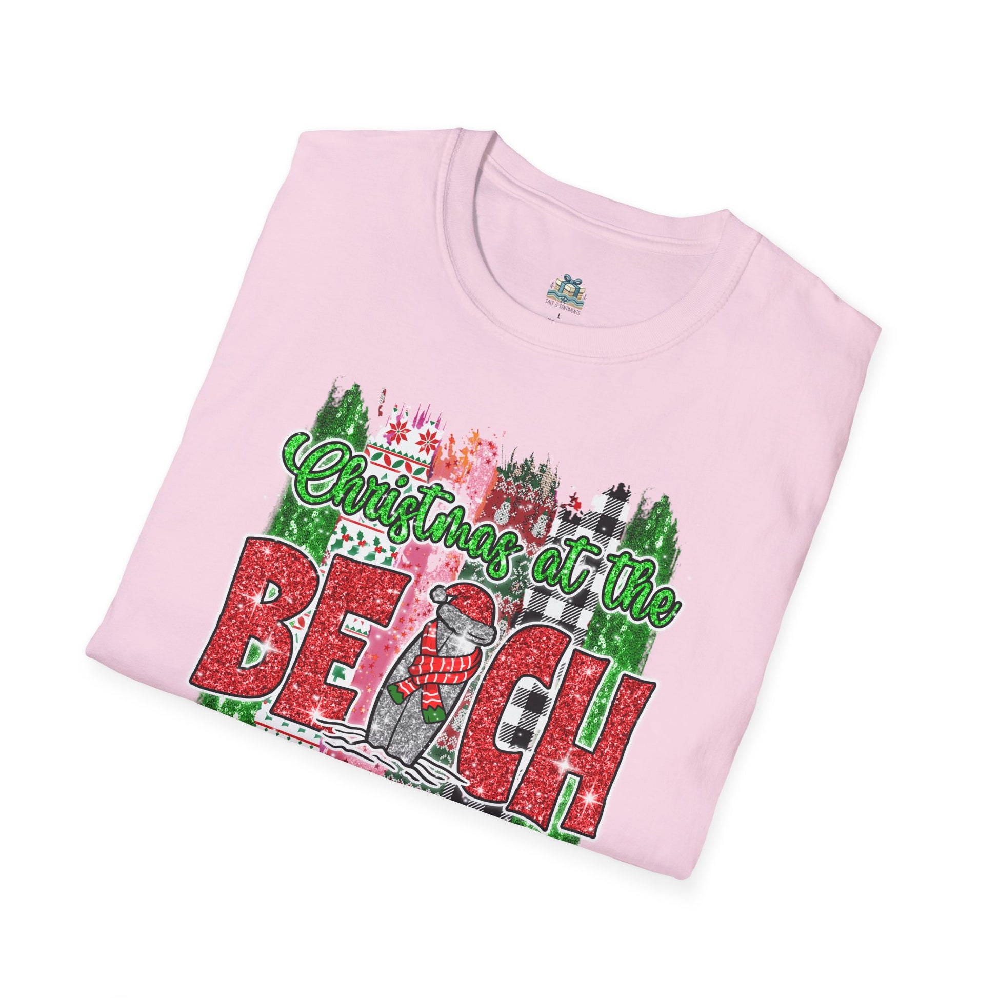 Folded pink t-shirt with 'Christmas at the Beach' design on a white background