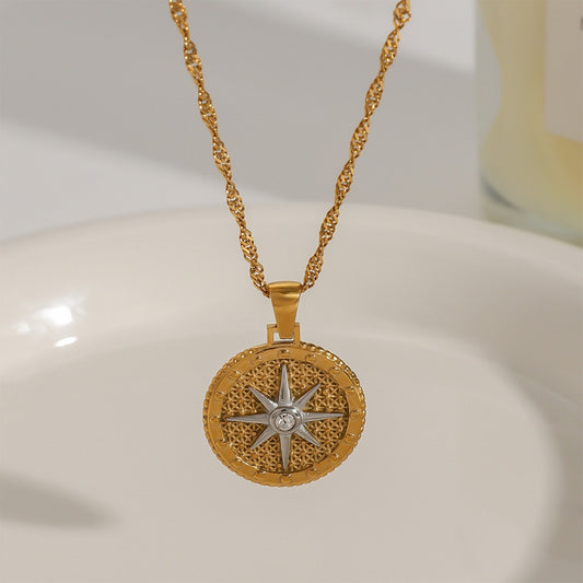 Gold necklace with a star-shaped pendant on a white surface