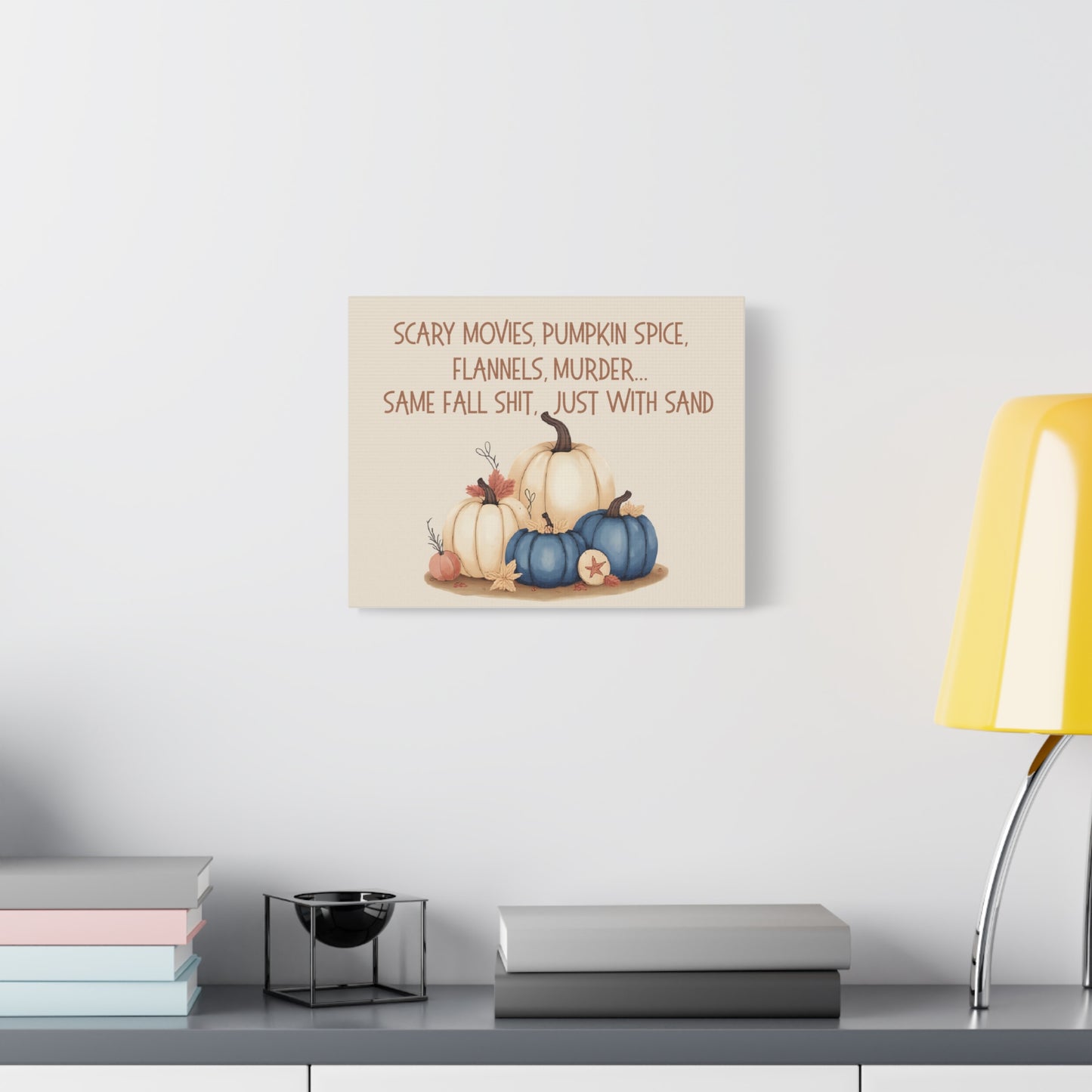 Decorative wall sign with pumpkins and text on a white wall above a shelf.