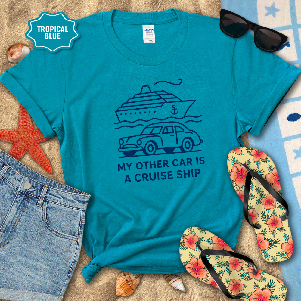 Blue t-shirt with a graphic and text 'My other car is a cruise ship' on a beach setting with flip-flops and sunglasses.