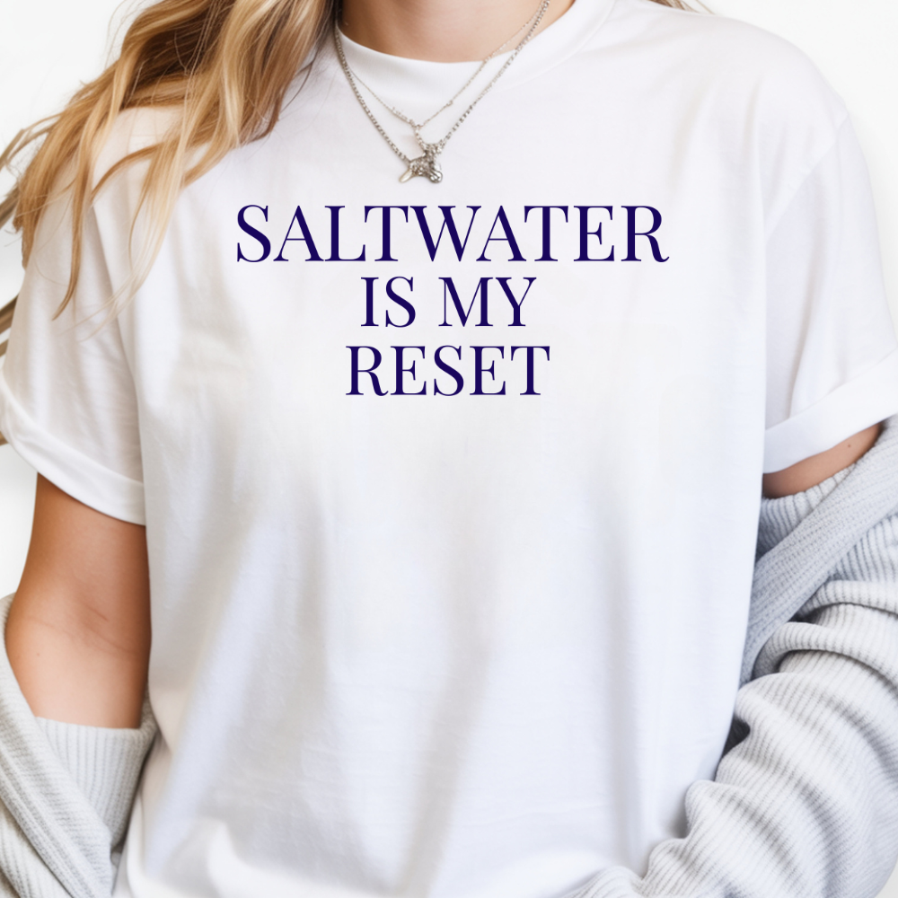 White t-shirt with 'SALTWATER IS MY RESET' text worn by a person.