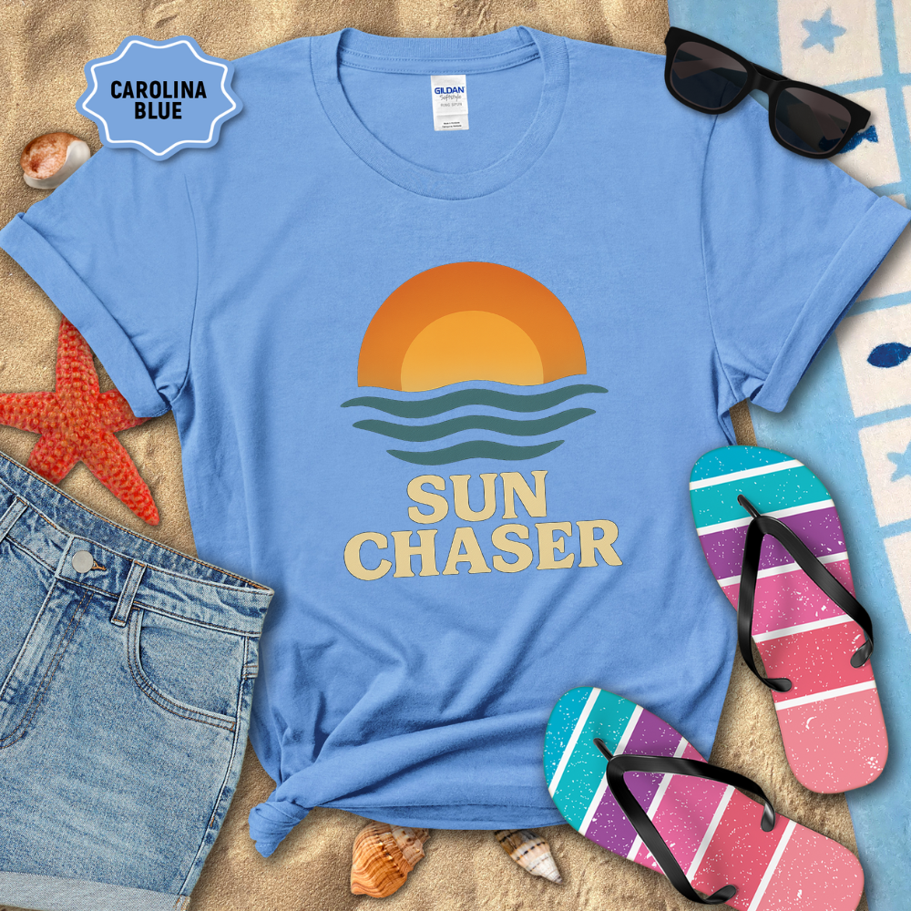 Blue t-shirt with 'Sun Chaser' design on a sandy background with sunglasses and flip-flops.