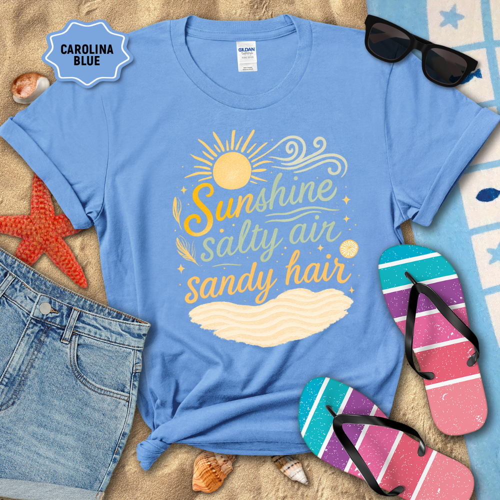 Blue t-shirt with 'Sunshine salty air sandy hair' design on a beach-themed background with sunglasses, flip-flops, and denim shorts.