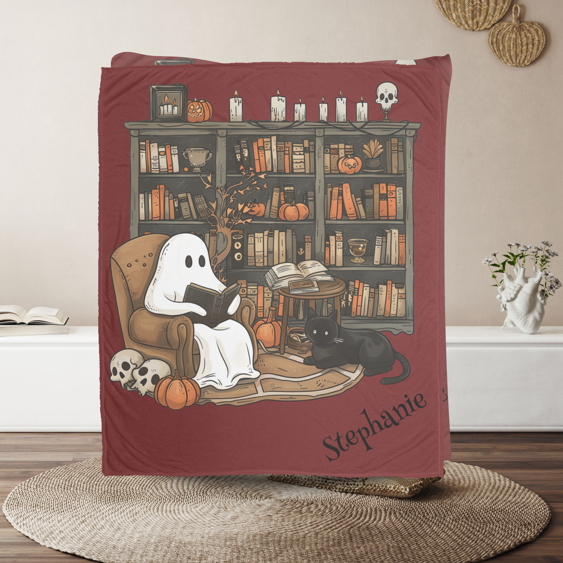 Blanket with ghost reading a book design, featuring 'Stephanie' on a wooden floor.