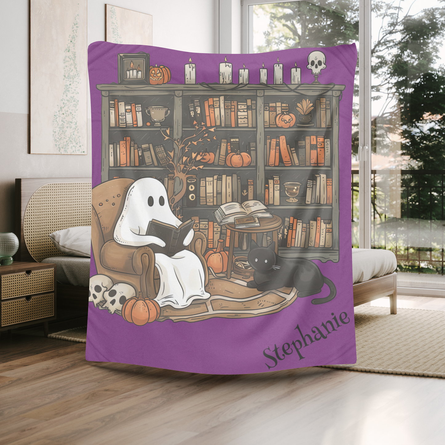 Halloween-themed blanket with ghost, cat, and books design on a bed in a room.