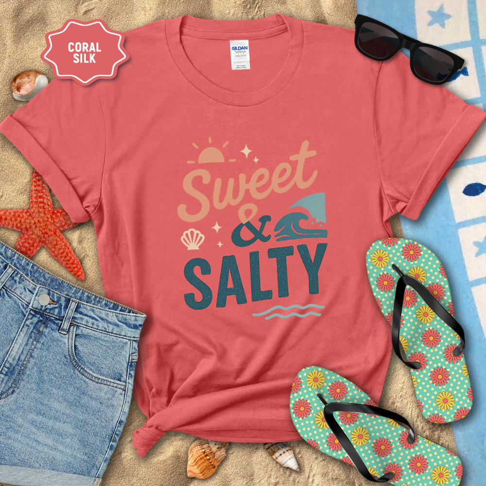 Coral t-shirt with 'Sweet & Salty' text on a beach setting with sunglasses, flip-flops, and denim shorts.