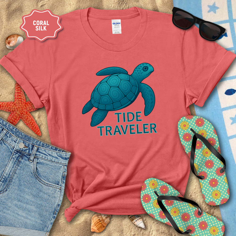Coral t-shirt with blue turtle graphic and 'Tide Traveler' text, surrounded by beach accessories.