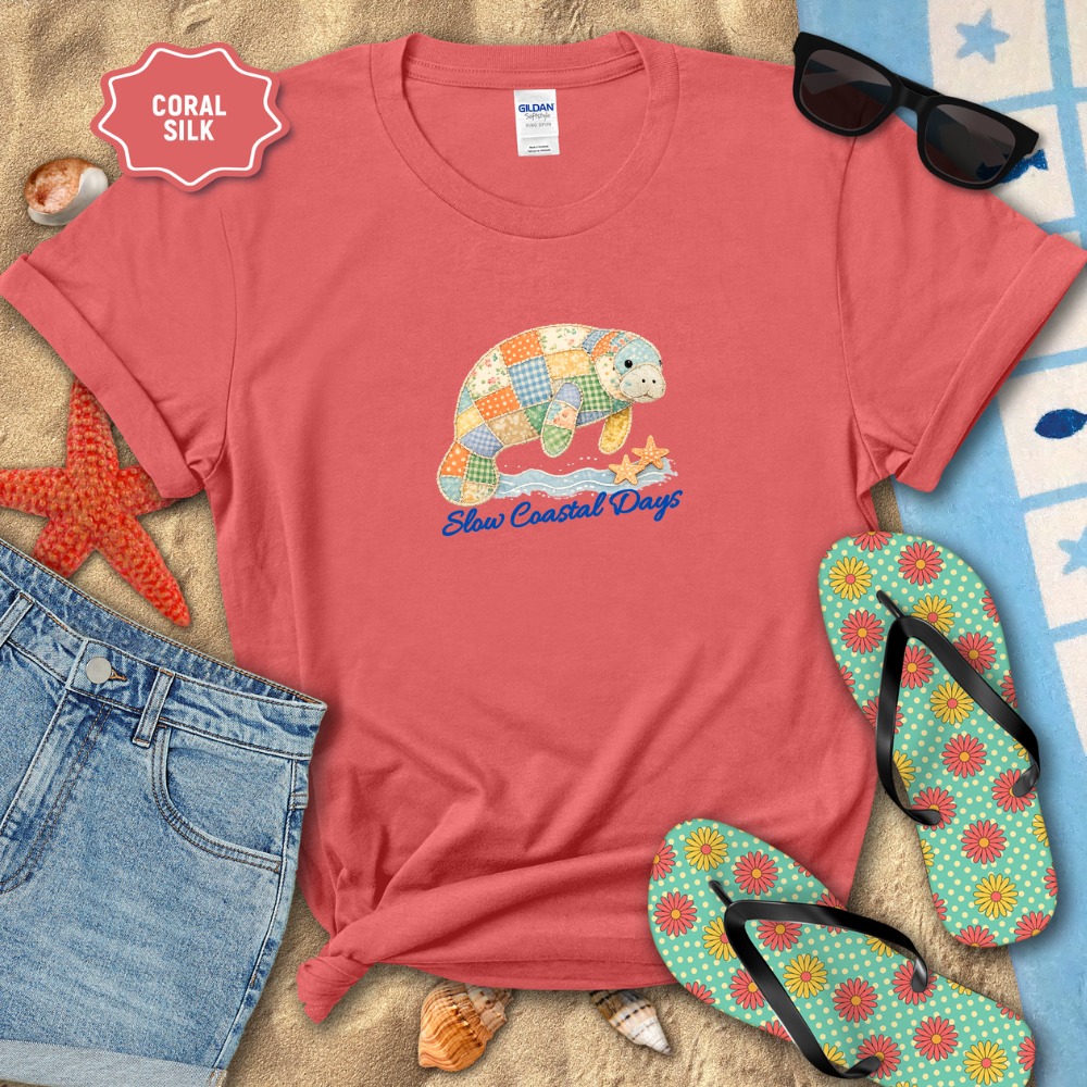 Red t-shirt with turtle graphic and 'Slooo Coastal Days' text, surrounded by beach accessories on sand.