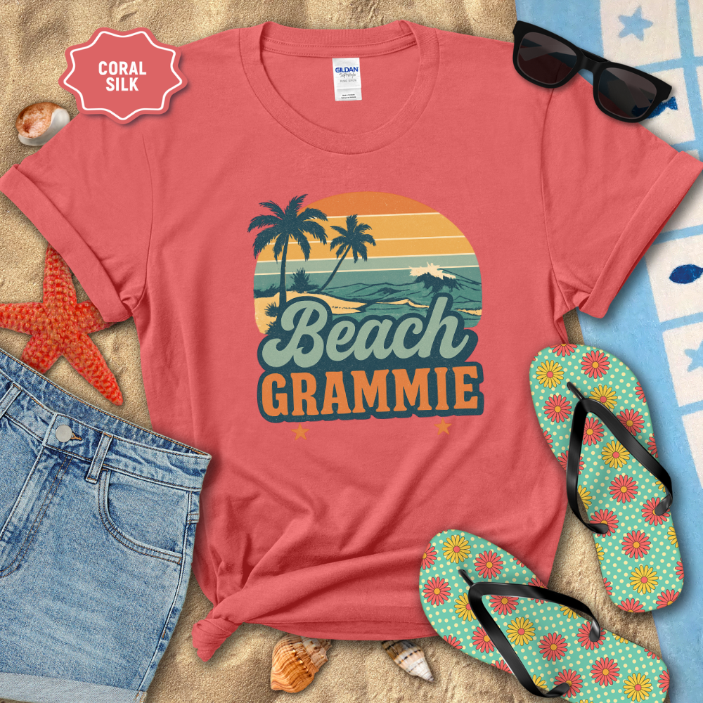 Coral t-shirt with 'Beach Grammie' design on a sandy background with flip-flops and sunglasses.
