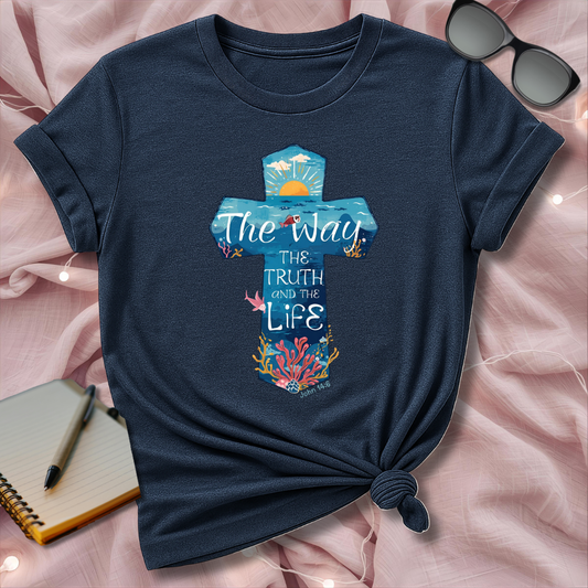 Navy blue t-shirt with a colorful graphic and text on a pink surface with sunglasses and a pen.