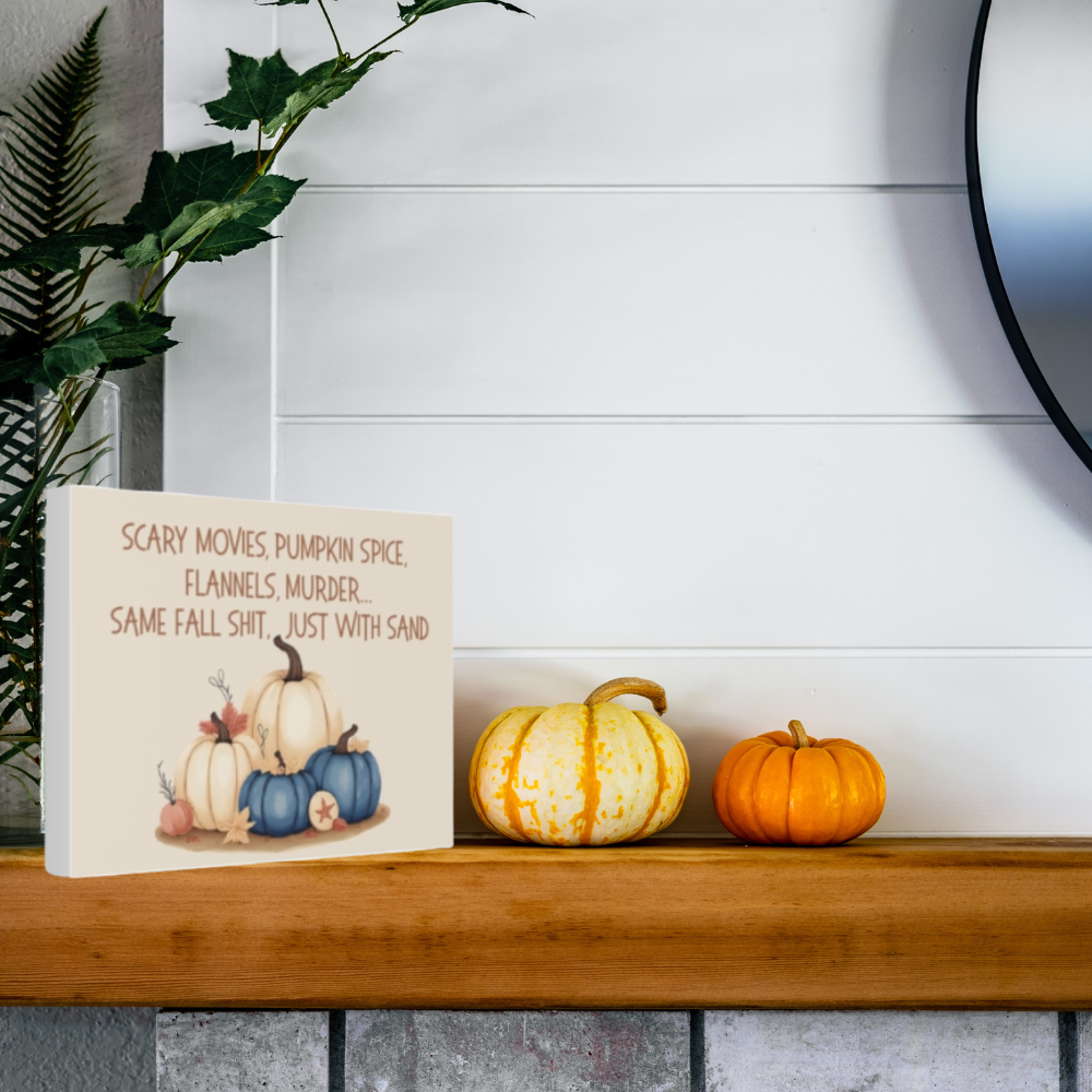 Decorative sign with pumpkins and text on a wooden shelf with pumpkins.