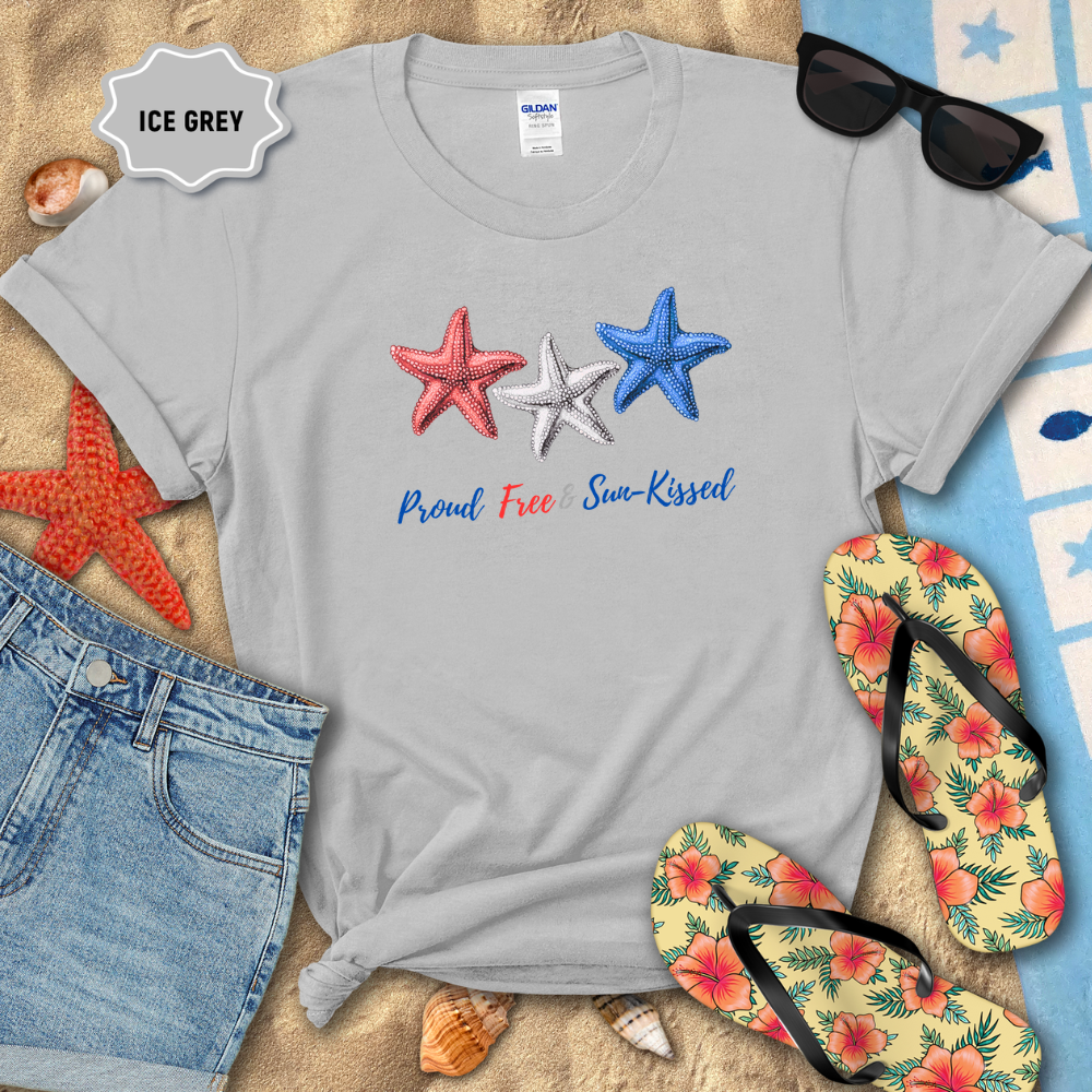 Gray t-shirt with starfish design and text on a sandy background with beach accessories.