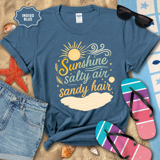 Blue t-shirt with 'Sunshine, Salty Air, Sandy Hair' design on a beach-themed background with sunglasses and flip-flops.