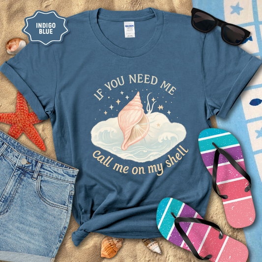 Blue t-shirt with beach-themed design and accessories on a sandy surface