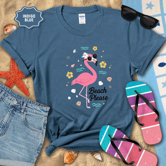 Blue t-shirt with a flamingo graphic and 'Beach Please' text, surrounded by beach accessories on sand.