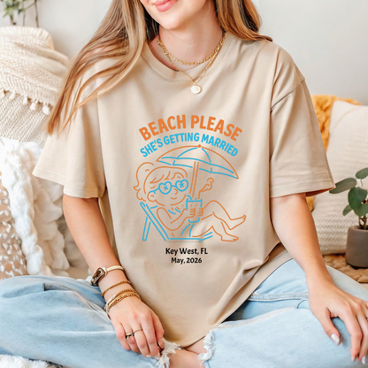 Person wearing a t-shirt with a beach-themed design and text.