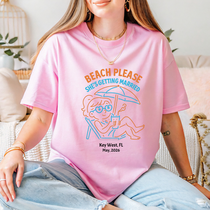 Person wearing a pink t-shirt with a beach-themed graphic and text.