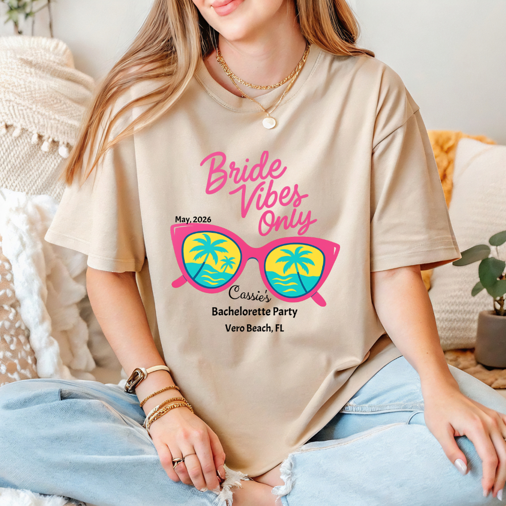 Person wearing a beige t-shirt with 'Bride Vibes Only' design, sitting on a couch.