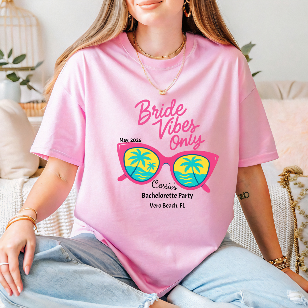 Person wearing a pink t-shirt with 'Bride Vibes Only' text and sunglasses graphic.