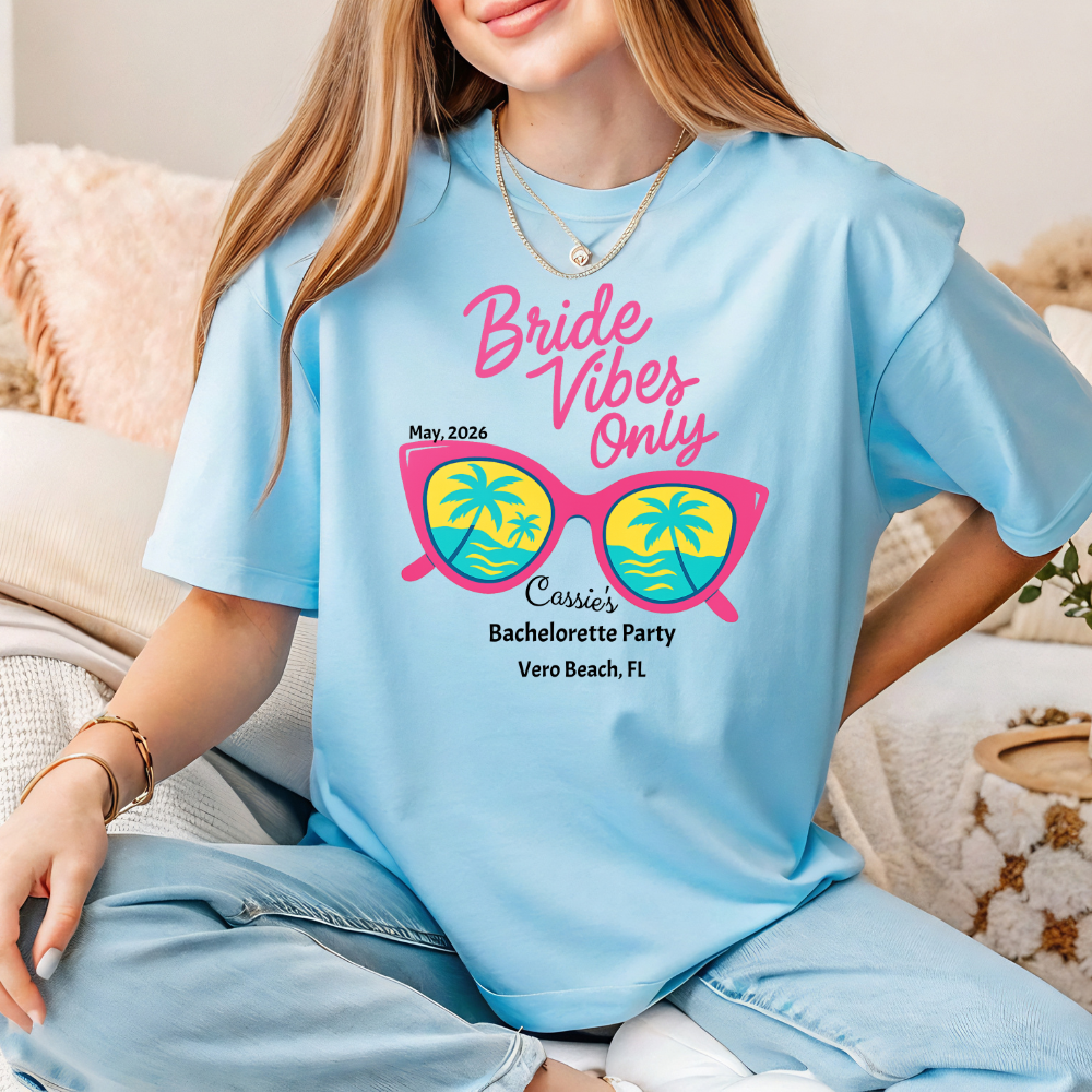 Person wearing a light blue t-shirt with 'Bride Vibes Only' text and sunglasses graphic.