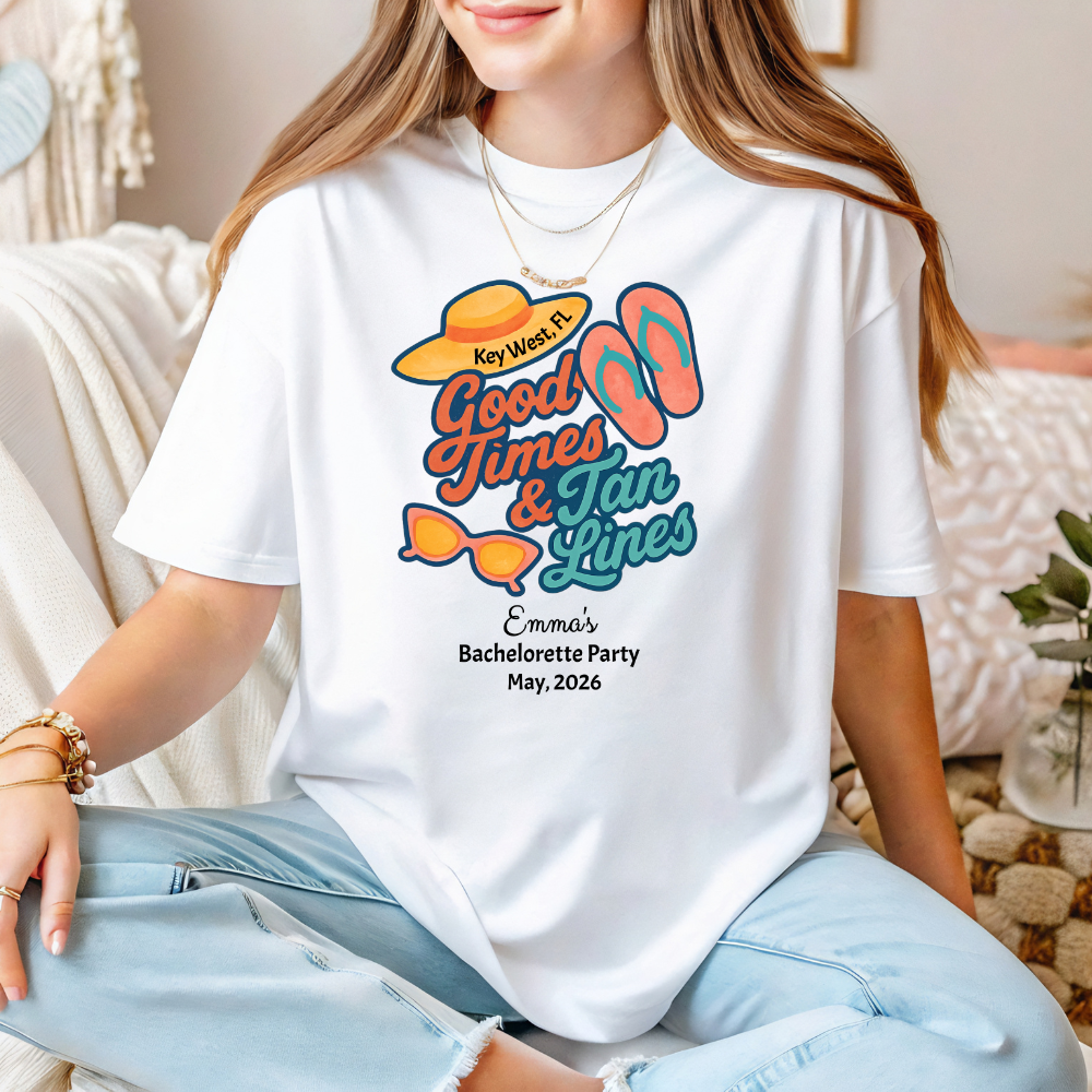 Person wearing a white t-shirt with 'Good Times & Tan Lines' design, sitting on a couch.