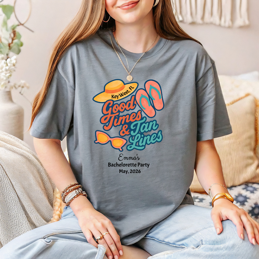 Person wearing a gray t-shirt with a colorful design and text, sitting on a couch.