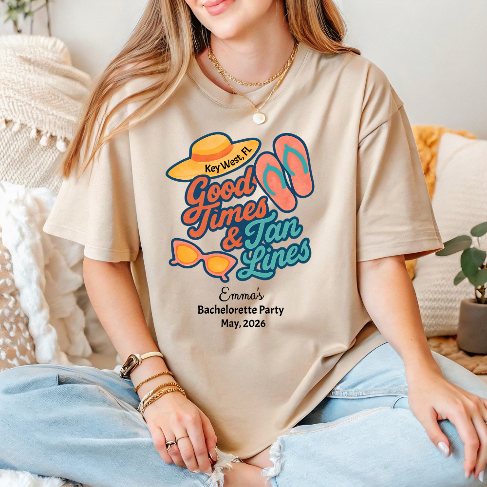 Person wearing a beige t-shirt with 'Good Times & Tan Lines' design, sitting on a couch.