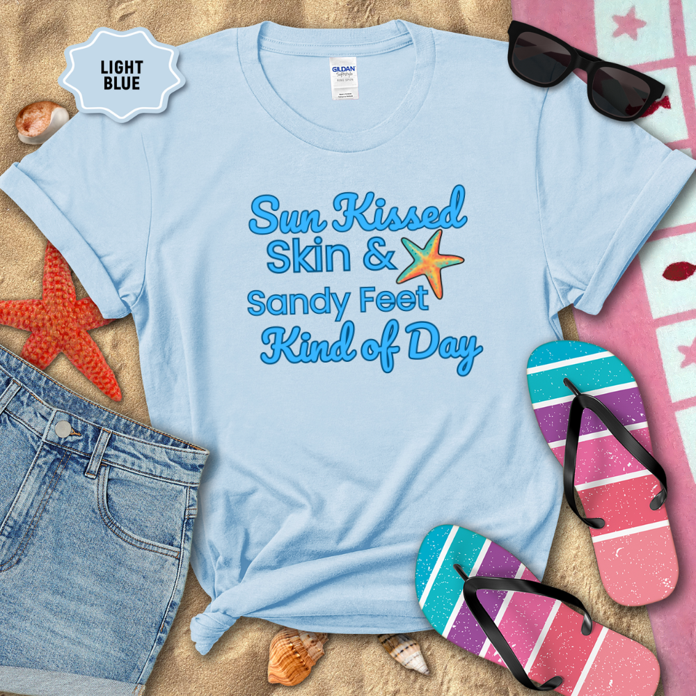 Light blue t-shirt with beach-themed text on sand with flip-flops and sunglasses.