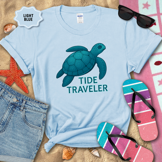 Light blue t-shirt with a turtle graphic and 'Tide Traveler' text, surrounded by beach accessories.