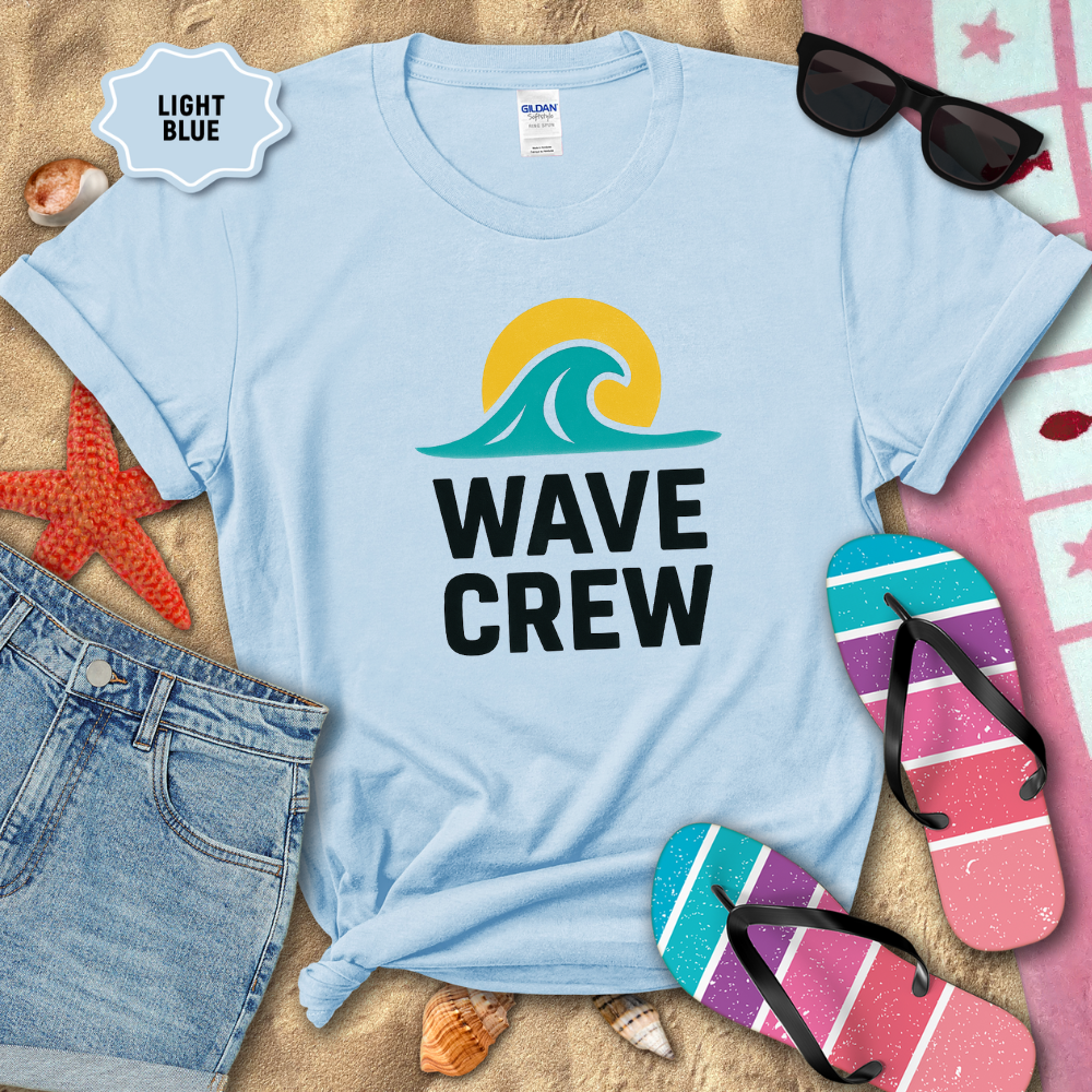 Light blue t-shirt with 'WAVE CREW' design on a sandy background with beach accessories.