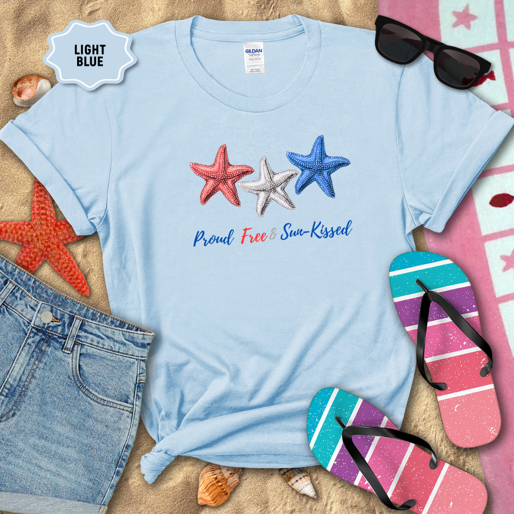 Light blue t-shirt with starfish design and text on a sandy background with beach accessories.