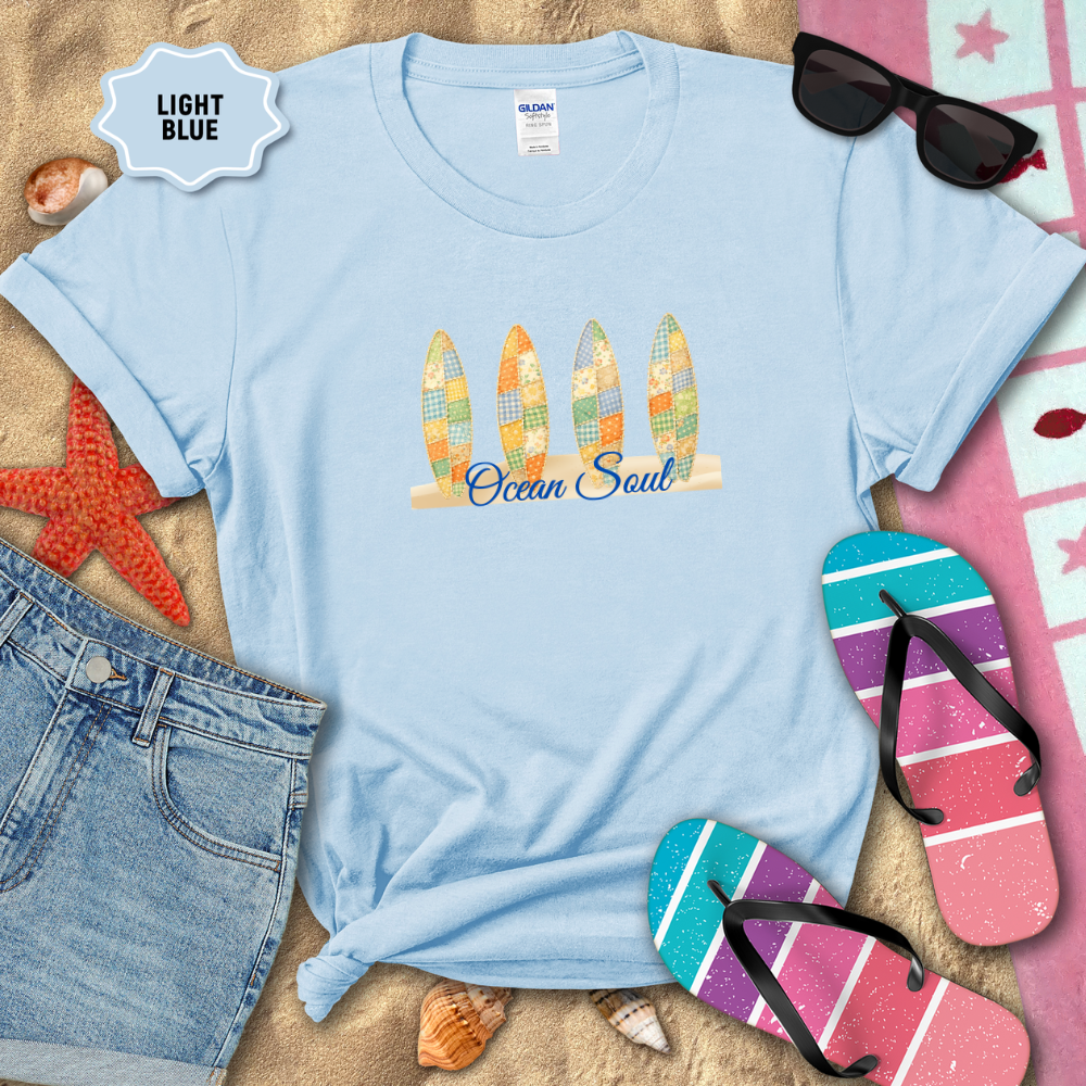 Light blue t-shirt with 'Ocean Soul' design on a sandy background with beach accessories.