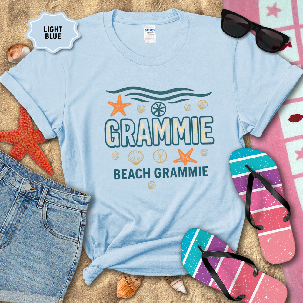 Light blue t-shirt with 'Beach Grammie' design on sand with beach accessories.